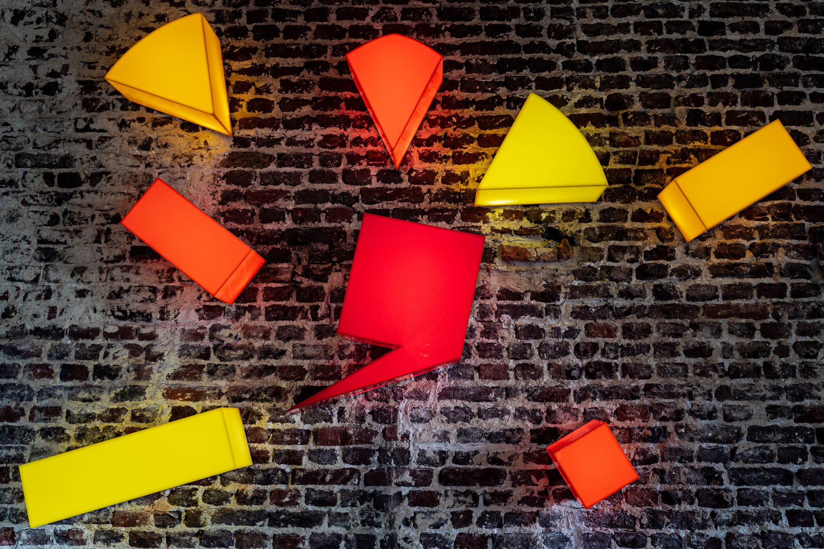 Illuminated geometric art installation on brick wall